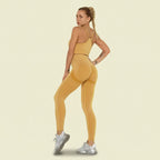 Woman wearing a mustard yellow athletic outfit on a white background