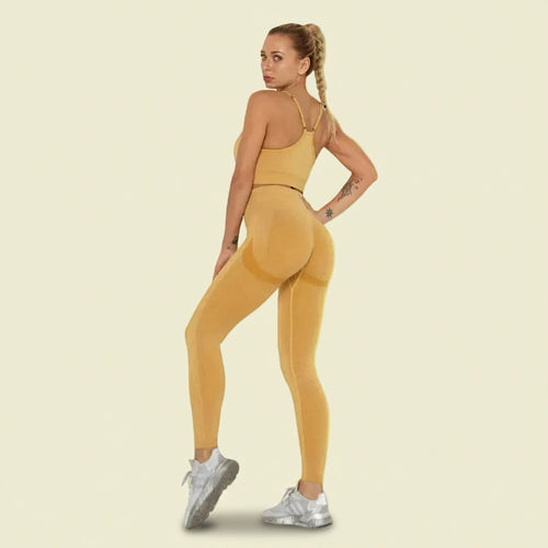 Woman wearing a mustard yellow athletic outfit on a white background