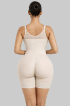 Woman wearing a beige shapewear bodysuit on a white background