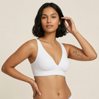 Woman wearing a white sports bra against a beige background