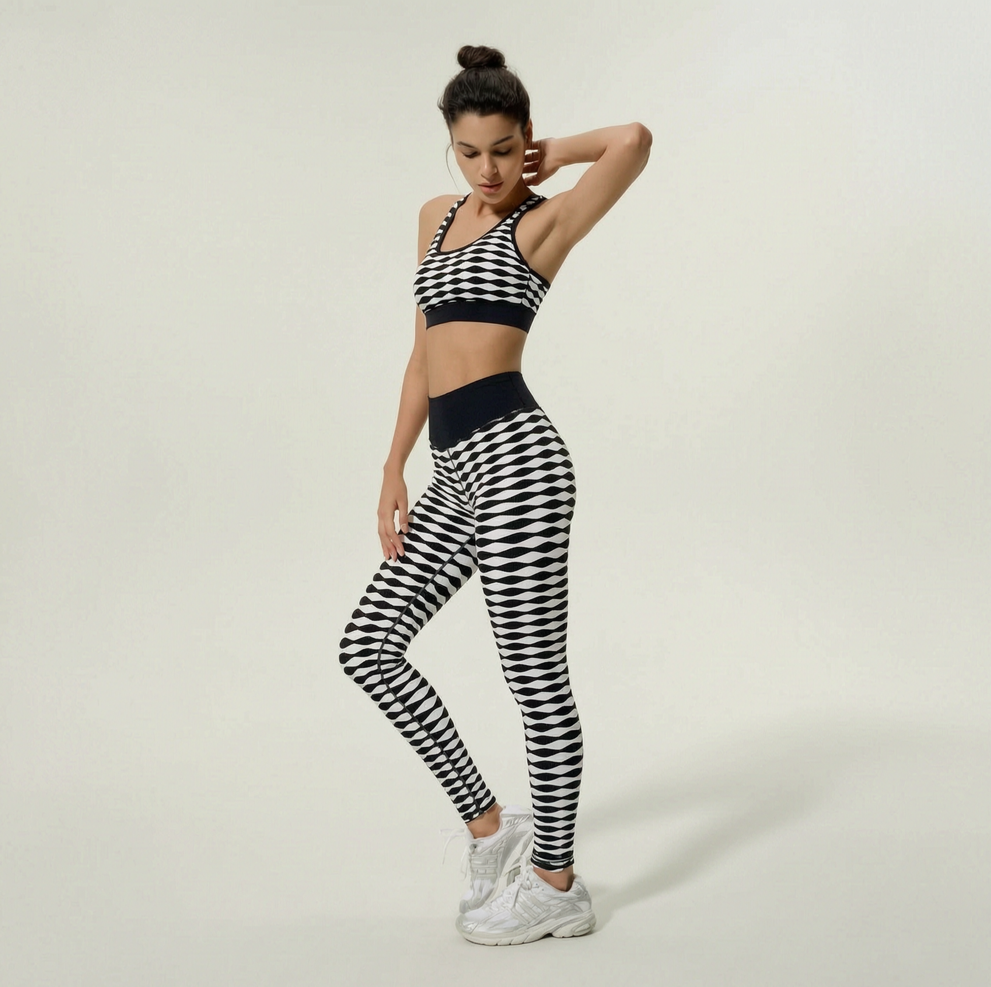 Woman wearing a black and white checkered sports bra and leggings set on a plain background
