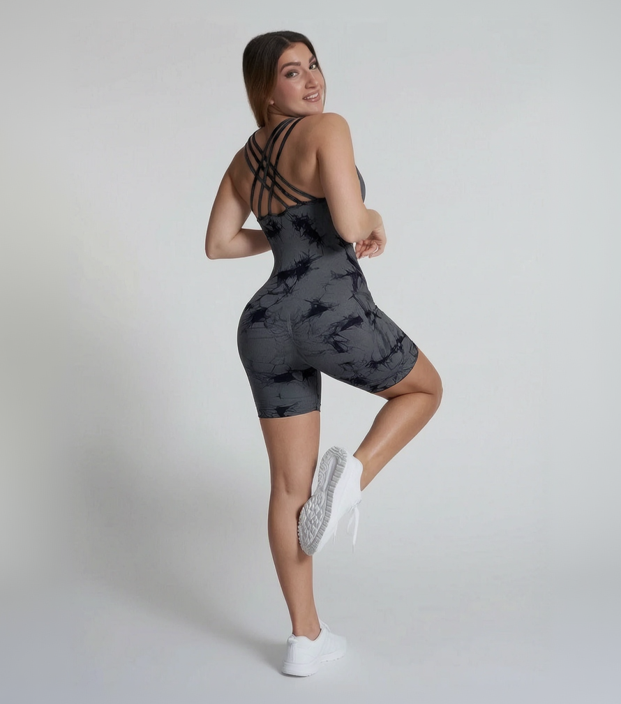 Woman wearing a black tie-dye romper on a plain background