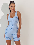 Woman wearing a blue tie-dye romper against a plain background